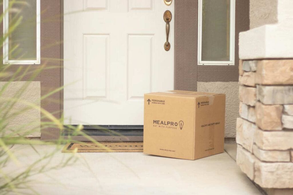 Delivered e-commerce order cardboard box placed at front door porch